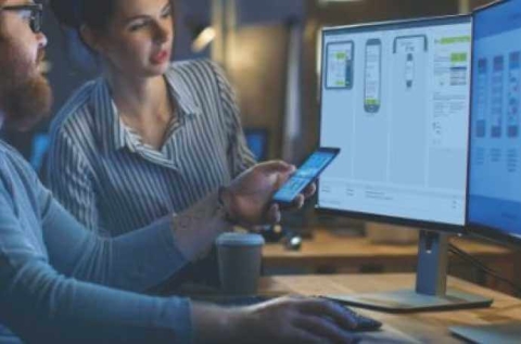 a man and a woman looking at screens and the man is showing the woman something on a mobile device