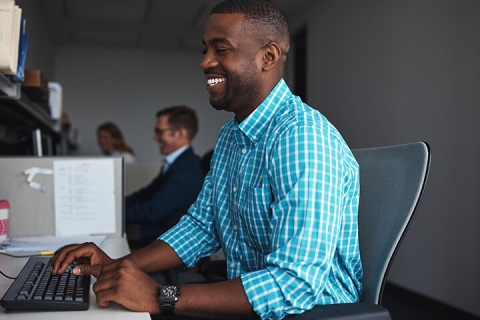 smiling middle aged man typing at work station