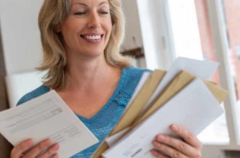 a blond woman holding letters and smiling