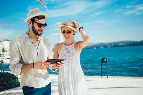 Happy vacationing couple looking at iPad together