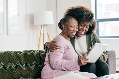Daughter reviewing information on tablet with senior mom