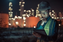 Petrochemical energy worker wearing hard-hat and using Smart tablet to communicate