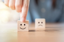 Turning point of customer satisfaction, fingers picking up a wooden block with smiling face