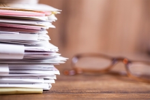 une pile de documents a cote des lunettes
