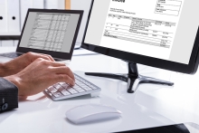 gros plan de la main d'un homme d'affaires vérifiant la facture sur l'ordinateur sur le lieu de travail