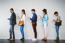 Des gens utilisent leurs portables en faisant la queue