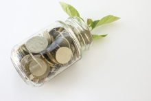 Jar with coins sprouting a small green plant symbolizing the growth of wealth