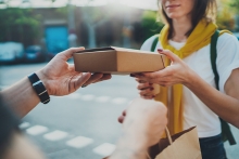 male with bicycle handing a shopping bag to a woman