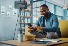 happy man looking at his phone in a living room