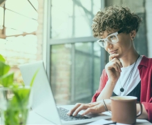 Frau mit Brille schaut auf ihren Laptopbildschirm