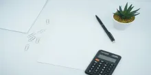Calculatrice, papier, trombones, stylo et succulent étalés sur un bureau