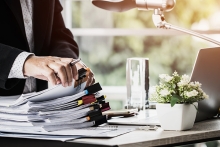 Businessman picking up report from list of files on a professional desk