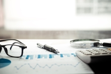 glasses on a table with financial documents underneath