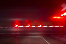 long exposure of railroad crossing arms with flashing red lights as a train speeds across a rural highway