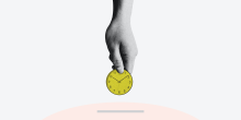 hand holding a yellow analogue clock