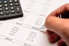 hand writing numbers on a numerical sheet with a calculator