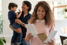 mother looking at the mail while dad and son playing at background