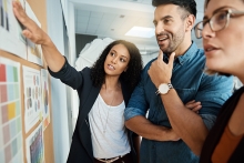 Group of People in a Brainstorming Session and Pointing at Wall