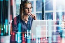 Businesswoman surrounded by graphs and looking at her computer
