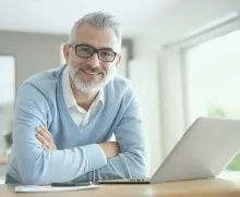 Man working at desk on laptop smiling at camera