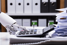 Robot hand typing on physical calculator