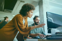 Coworkers working together and discussing at computer screen