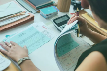 Businesswoman looking through documents on desk with calculator