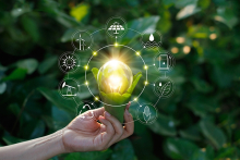 Hand holding light bulb with sustainability icons